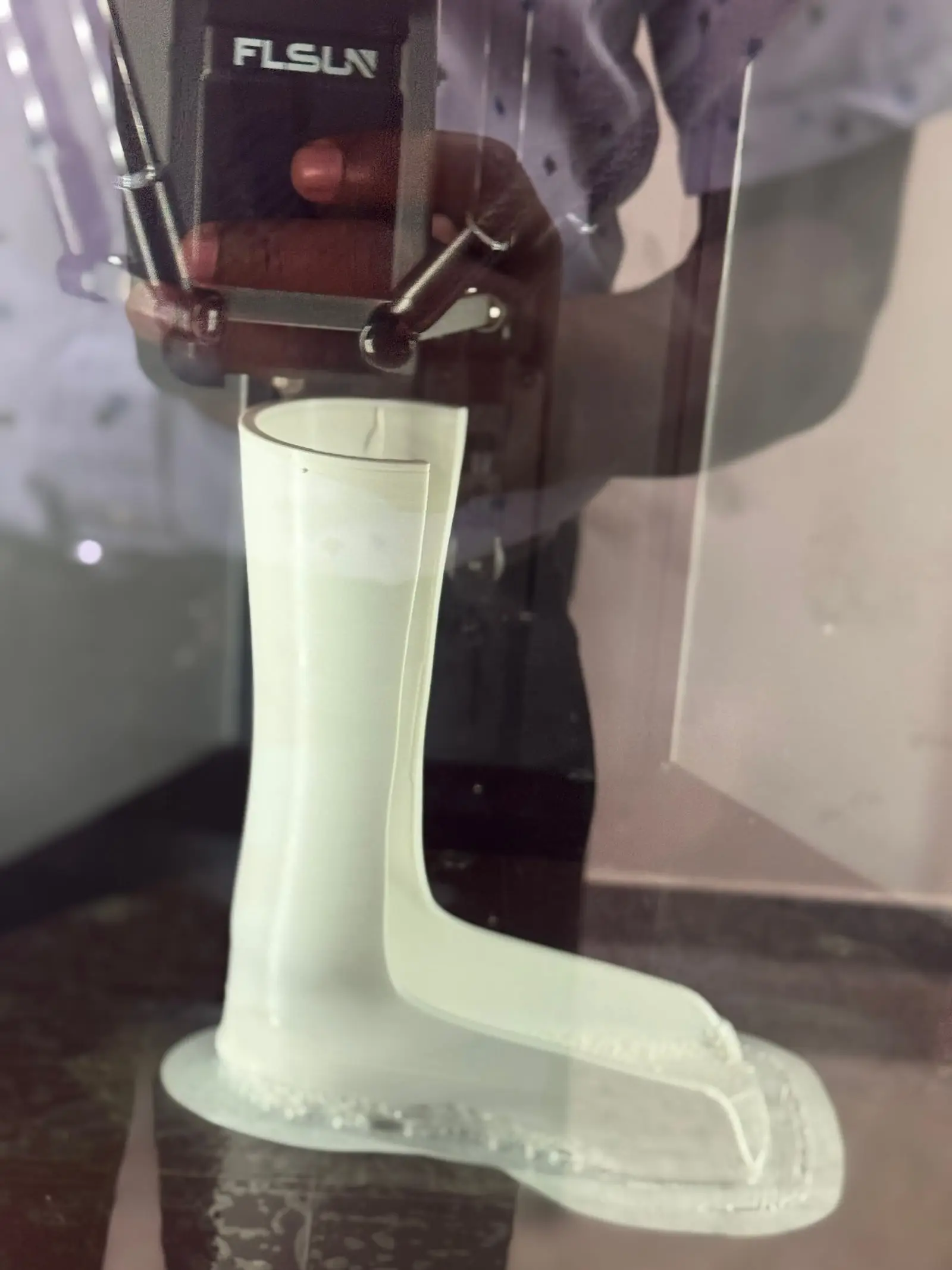 A white ankle-foot orthosis being 3D printed inside a printer at CoRSU.