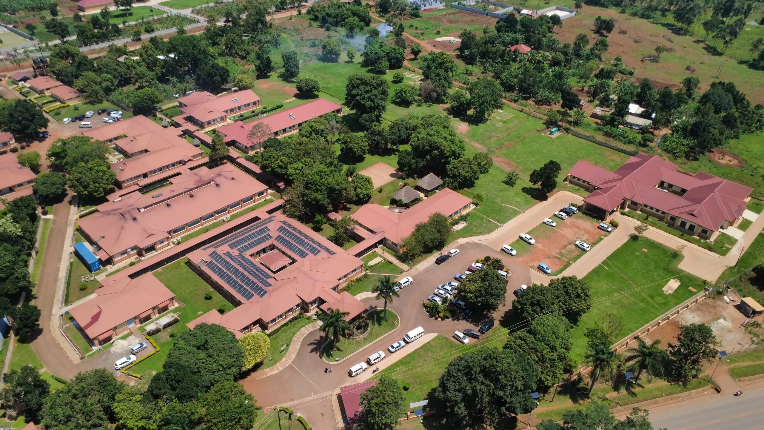 Aerial view of the CoRSU hospital campus at Kisubi: red-roofed buildings among trees and lawns, beside Entebbe Road.