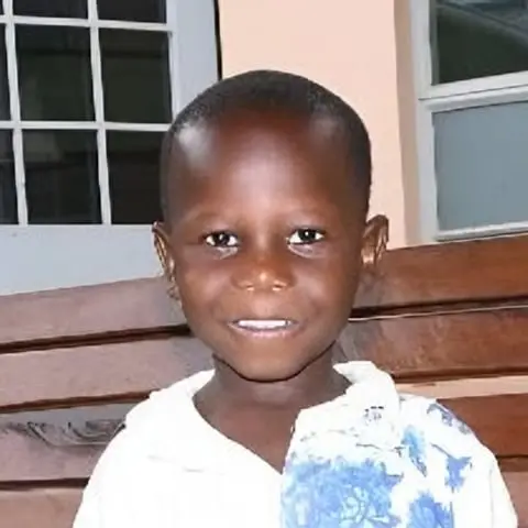 Mark, a young boy in a white shirt, smiling.
