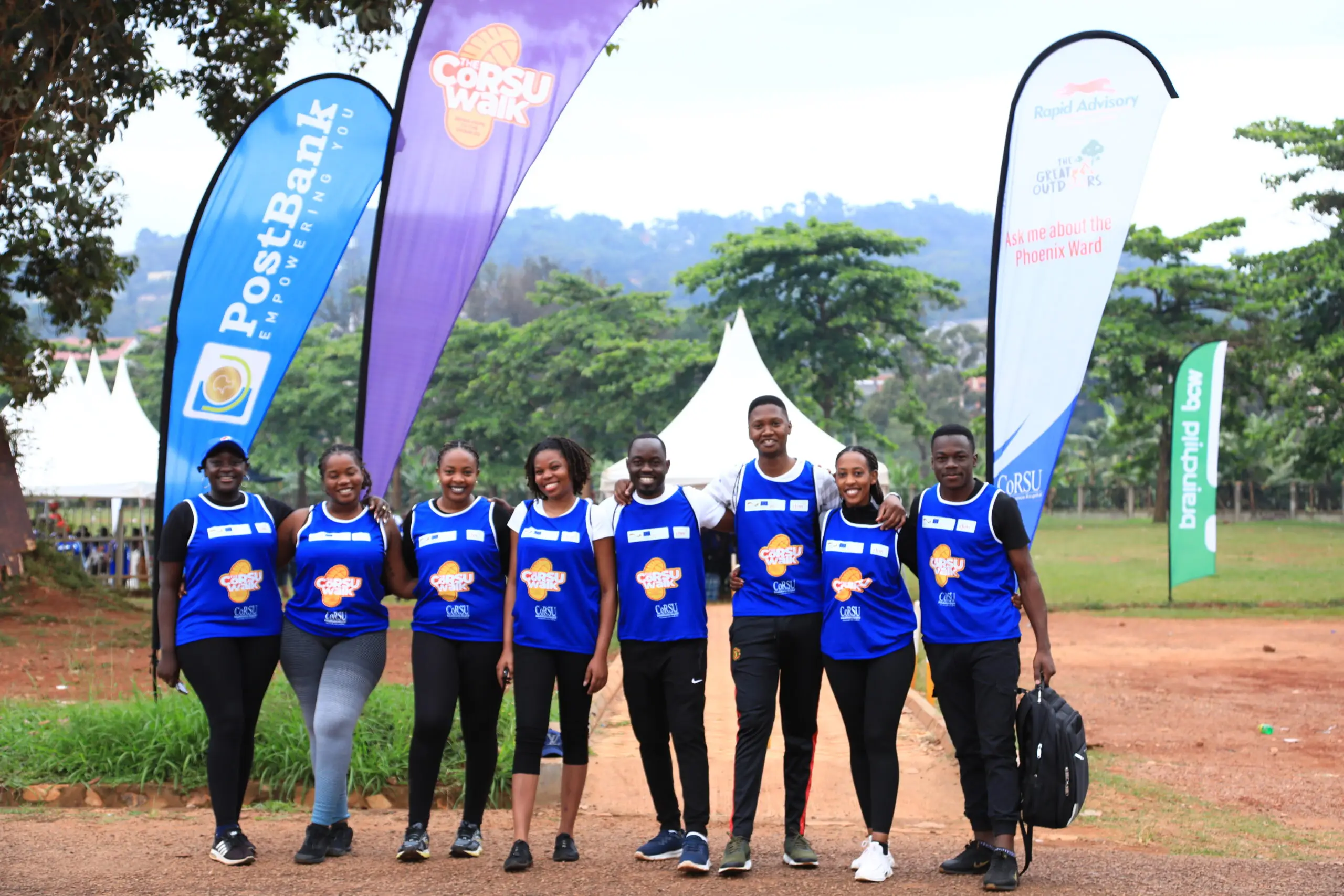 A group of young people pose in front of sponsor flags at the CoRSU Walk.