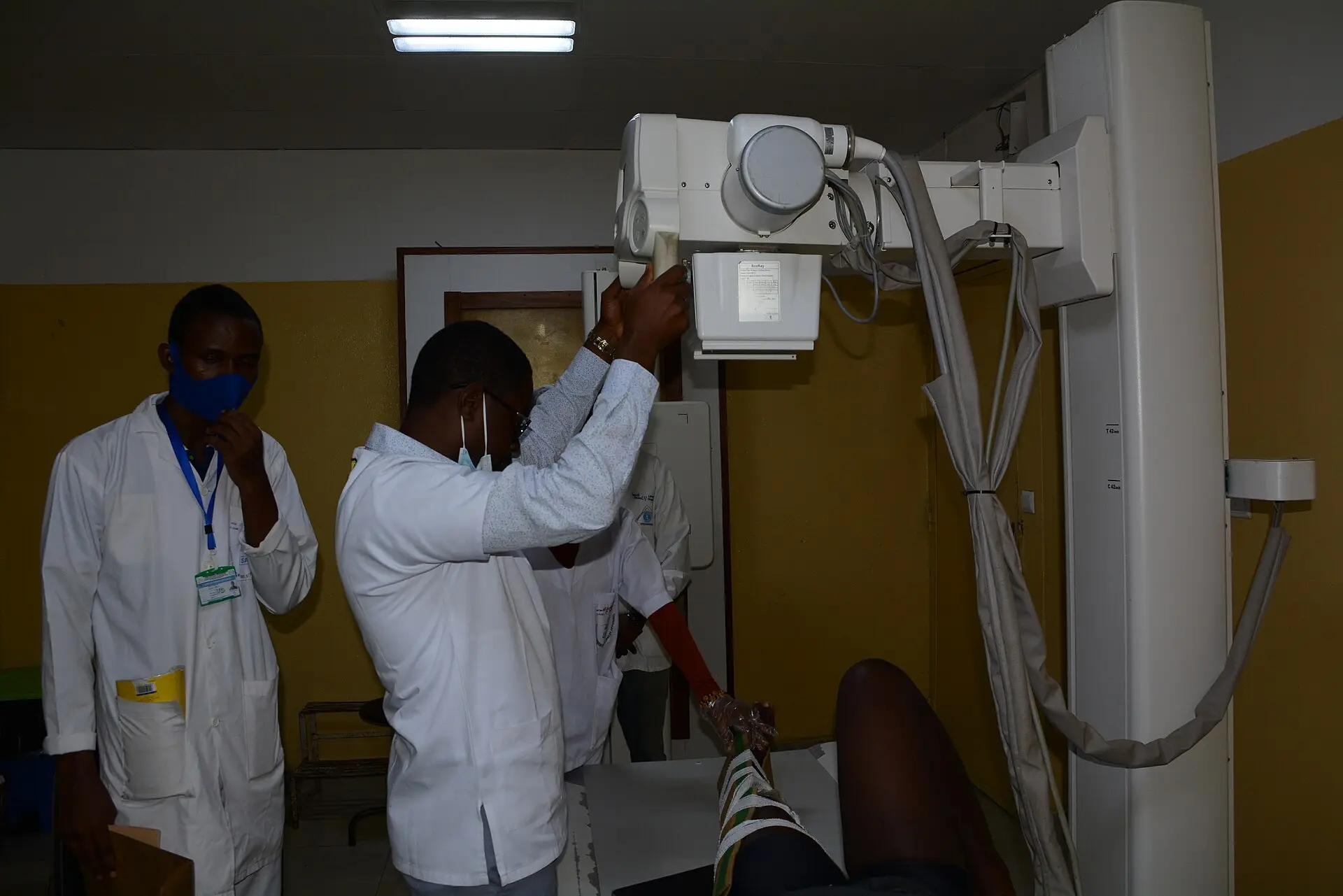 Two radiographers position an X-ray machine over a patient’s leg. Illustrative photo.